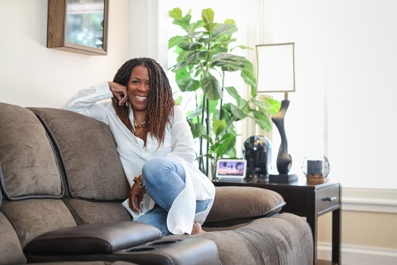 A woman sitting on top of a couch talking on the phone.